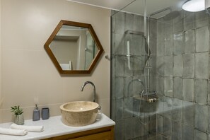 A bathroom with a round sink, a mirror, and a shower enclosure. - Casa Irene (Chania)