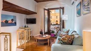 A cozy living room with a wooden ceiling, a sofa with patterned cushions, a round wooden coffee table, and a TV on the wall. - Casa Irene (Chania)