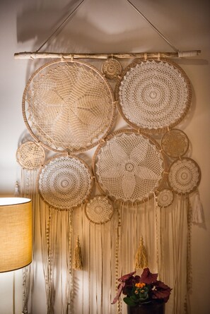 A wall with large circular crochet patterns and hanging tassels. - Casa Irene (Chania)