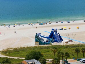 A beach with a large blue water slide and a sandy shore.