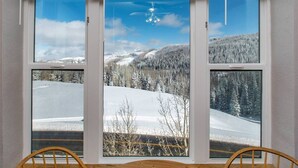 A room with a large window overlooking a snowy landscape with trees and a clear sky. - Heart of Rock-n-Roll (2303) | Amazing Views (Brian Head)