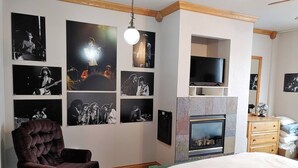 A bedroom with a large bed, a dark armchair, a fireplace, and multiple framed black and white photographs on the wall. - Heart of Rock-n-Roll (2303) | Amazing Views (Brian Head)