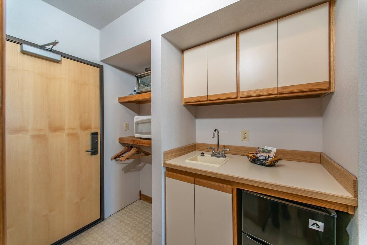 A compact kitchen with wooden cabinets, a microwave, a sink, and a refrigerator.