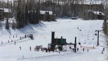 A ski resort with a ski lift, snow-covered trees, and a building in the background.