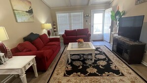 Ein Wohnzimmer mit einem roten Sofa, einem weißen Couchtisch und einem schwarz-beigen Teppich.