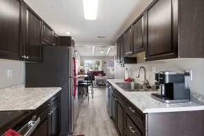 Une cuisine moderne avec des meubles de couleur sombre, des appareils électroménagers en acier inoxydable et un plan de travail en marbre.