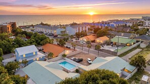 Un quartier résidentiel en bord de mer, avec des maisons, une piscine et une vue sur le coucher de soleil.