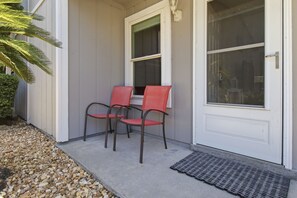 A house exterior with a front door, two chairs, a small garden area with pebbles, and a palm tree. - Gulfcrest unit 2. 1 Block From Beach!! Private Swimming Pool!! 2 Bed 2 Bath (Miramar Beach)