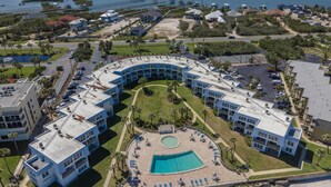 Ein Resort mit zentralem Pool, verbundenen Gebäuden und einem Hafen.