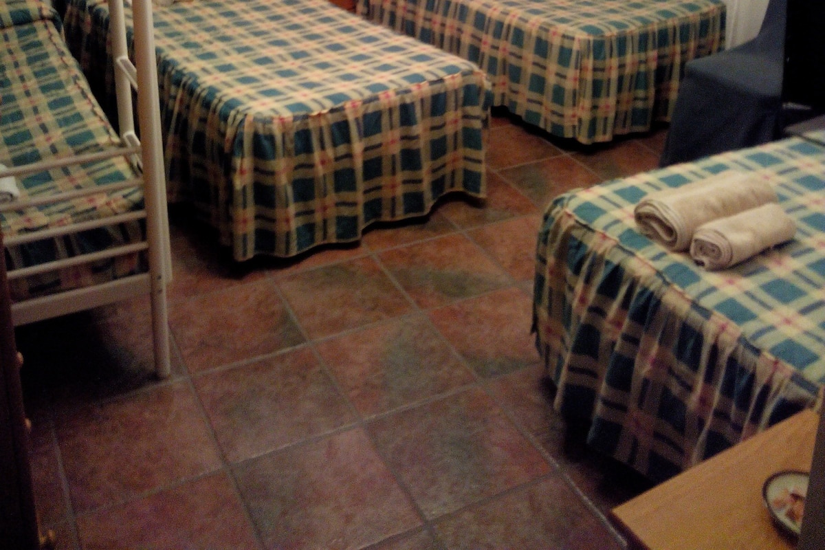 Una habitación con literas, dos camas individuales, un televisor y una mesita.