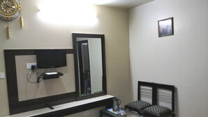 Hotelkamer met een grote spiegel, een flatscreen televisie, een klein tafeltje met een waterkoker en een stoel.