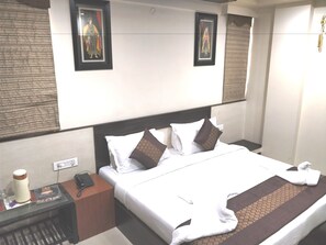A hotel room with a large bed, two nightstands, a coffee machine, and artwork on the walls. - Hotel Jinendra Palace (Jaipur)