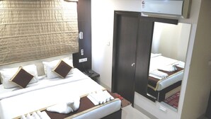 Een hotelkamer met een bed, nachtkastje en een spiegel.