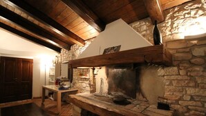 Una chimenea de piedra rústica con un banco de madera frente a ella, una pared de piedra y un techo de madera.