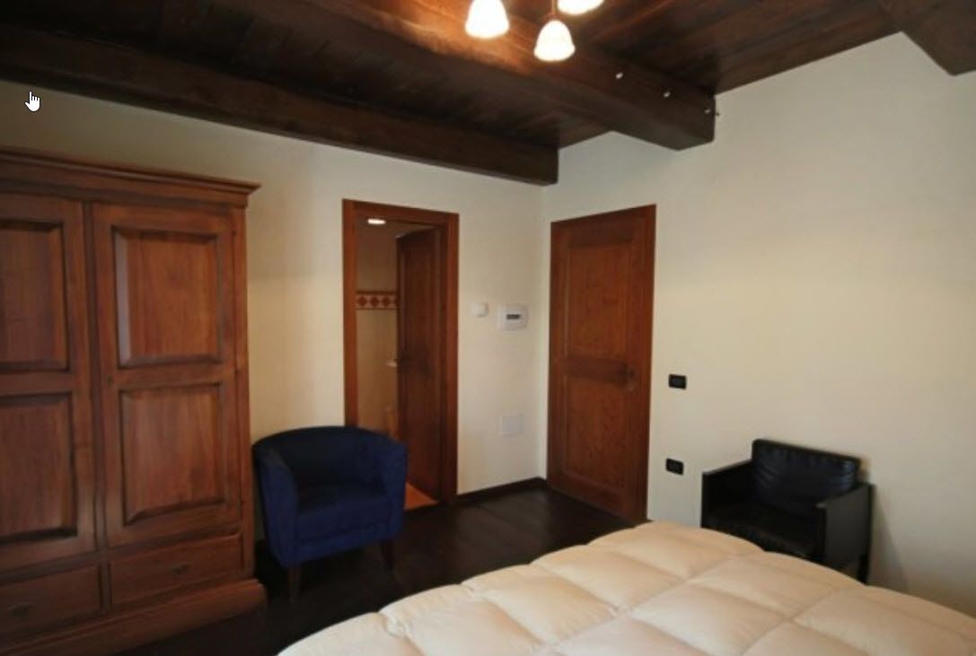 A bedroom with a bed, a wardrobe, a chair, and a door.