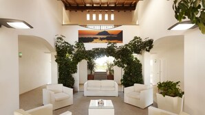 Un hall amplio con un sofá blanco, una mesa de centro de vidrio y plantas en macetas.