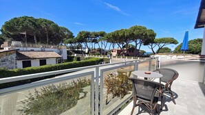 Un balcón con mesa y sillas, con vista a una zona residencial con árboles y casas.