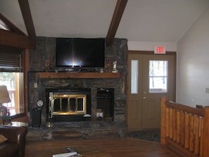 Cozy living room with a fireplace, flat-screen TV, and wooden ceiling with exposed beams.