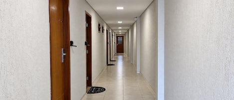 Un pasillo largo y estrecho con puertas a ambos lados, que conduce a habitaciones individuales.