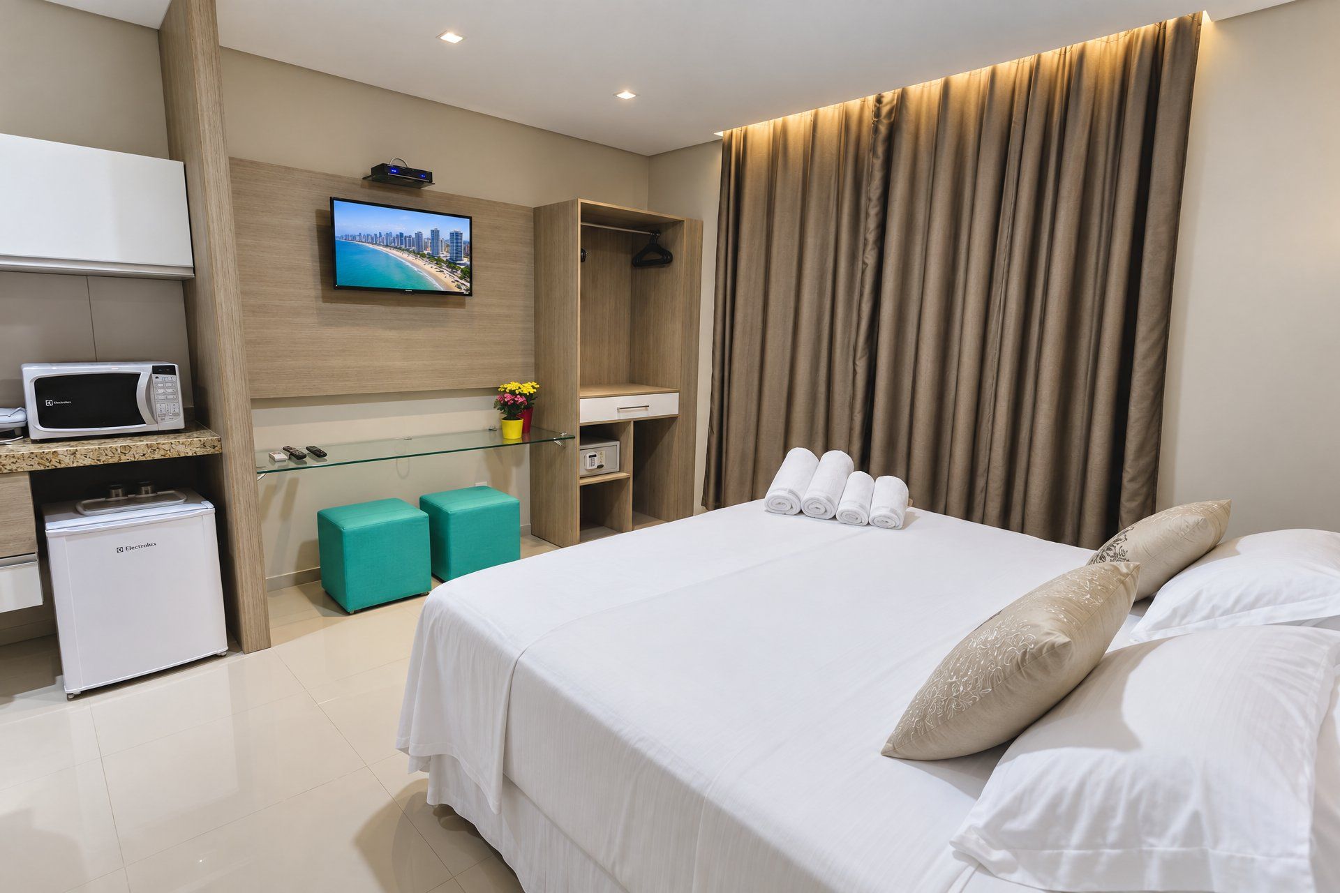 Habitació d'hotel amb llit, televisió, minibar i zona de seients.