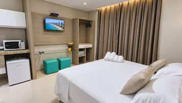 Habitación de hotel con cama, televisor, minibar y zona de estar.