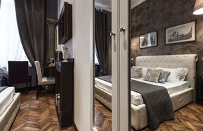 A hotel room with a large bed, a desk, a chair, and a wardrobe. - Vite Suites (Rome)