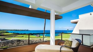A balcony with a view of the ocean and a golf course. - 2BR ocean and sunset views in Mauna Lani point (Kamuela)