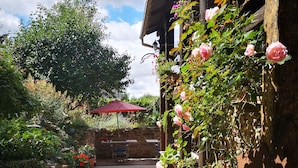 A garden pathway leading to a wooden building with a red umbrella and potted plants.