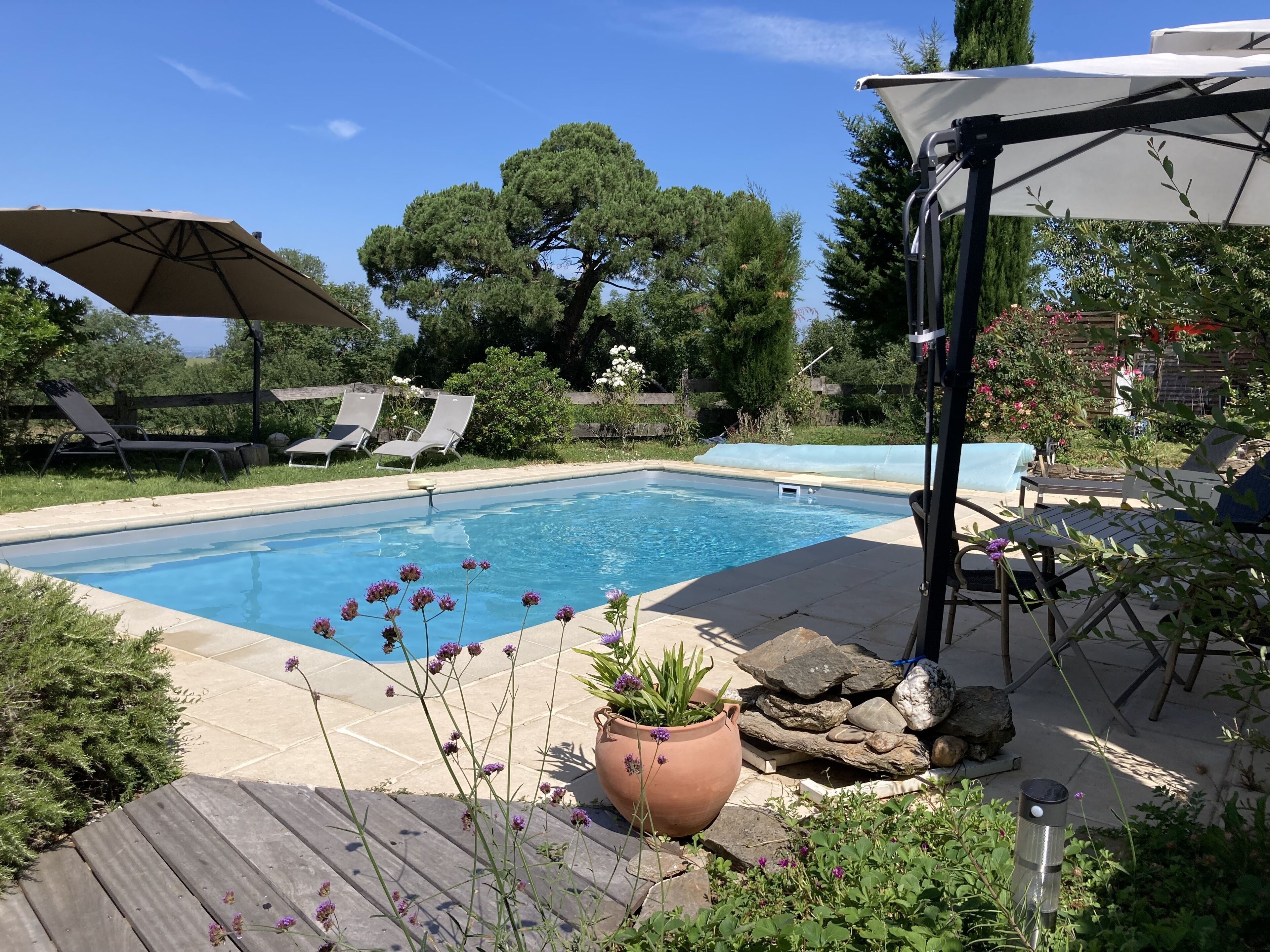 Una piscina con sillas de descanso y una pérgola.
