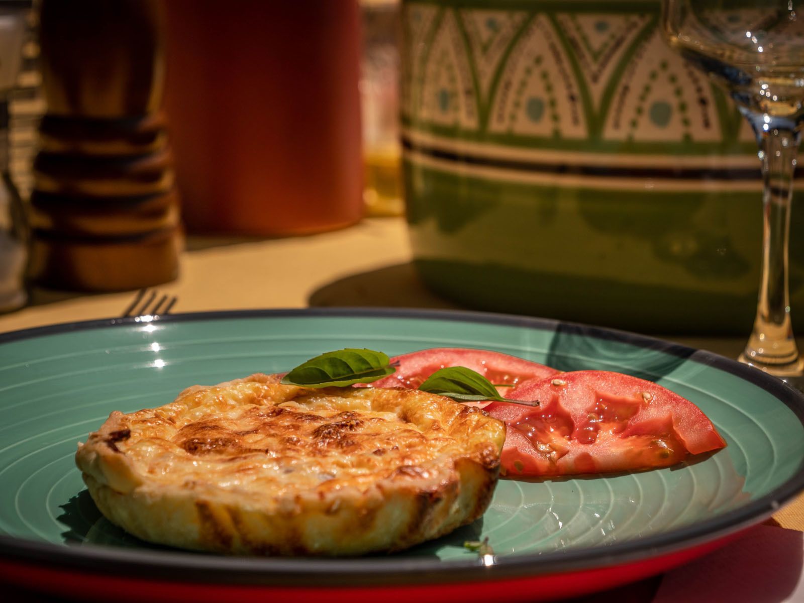A plate with a grilled cheese sandwich and a slice of tomato on a blue plate.