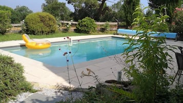 Una piscina al aire libre, sillones reclinables de piscina