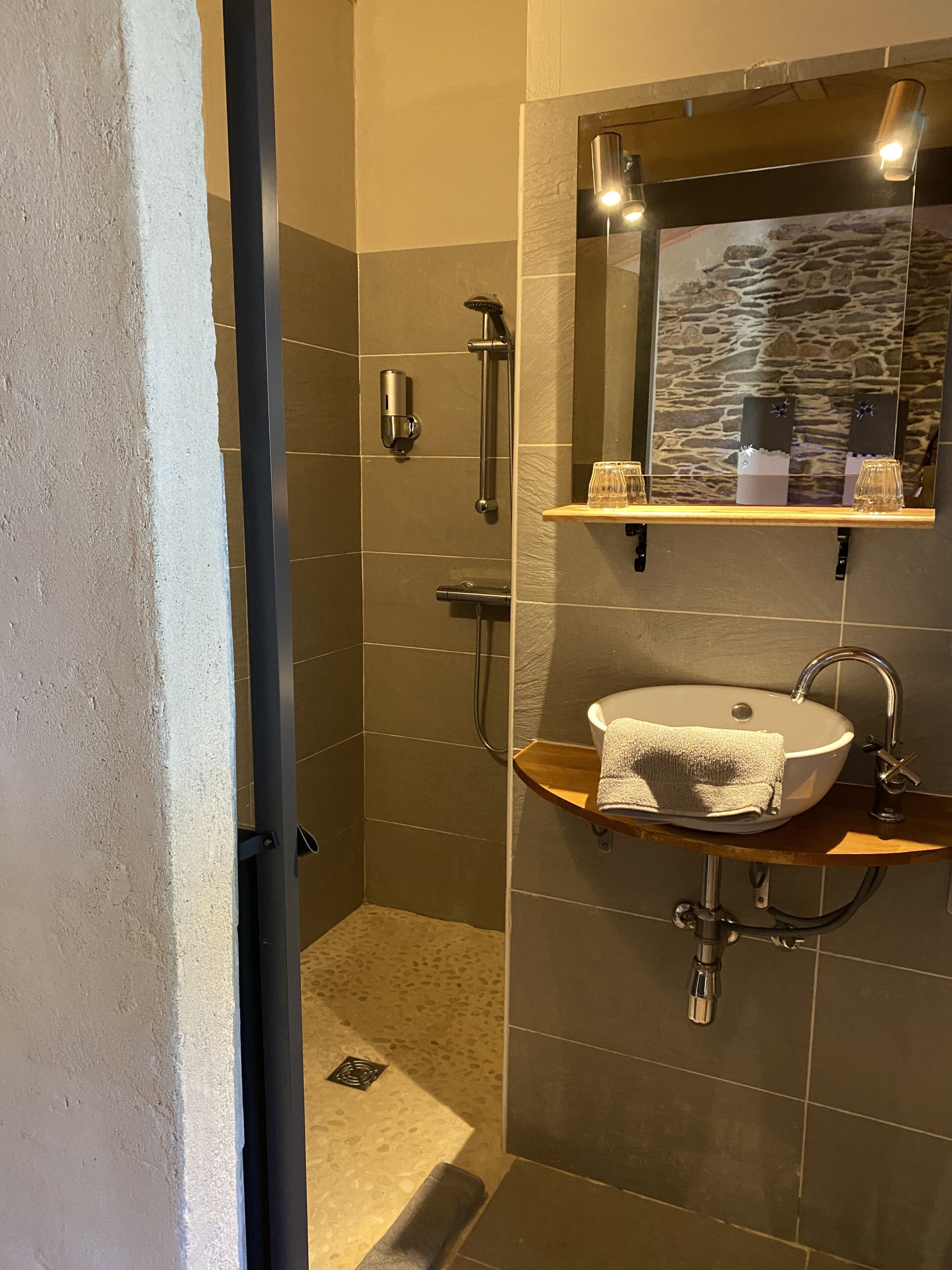 Une salle de bain moderne avec une douche, un lavabo et un miroir.