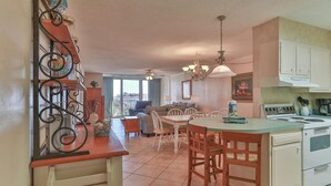 A kitchen with a dining area, a balcony, and a view of the outdoors.