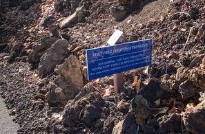 A sign in a rocky area with text about a historic fishpond preserve.