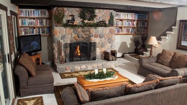 Una sala acogedora con chimenea de piedra, un televisor y dos sofás.