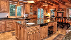 Eine geräumige Küche mit Holzschränken, Granit-Arbeitsplatten und Pendelleuchten.
