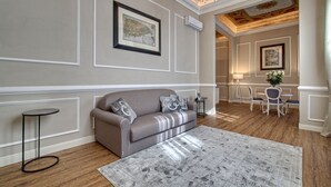Ein modernes Wohnzimmer mit einem grauen Sofa, einem runden Beistelltisch, einem gemusterten Teppich und einer Kronleuchter.