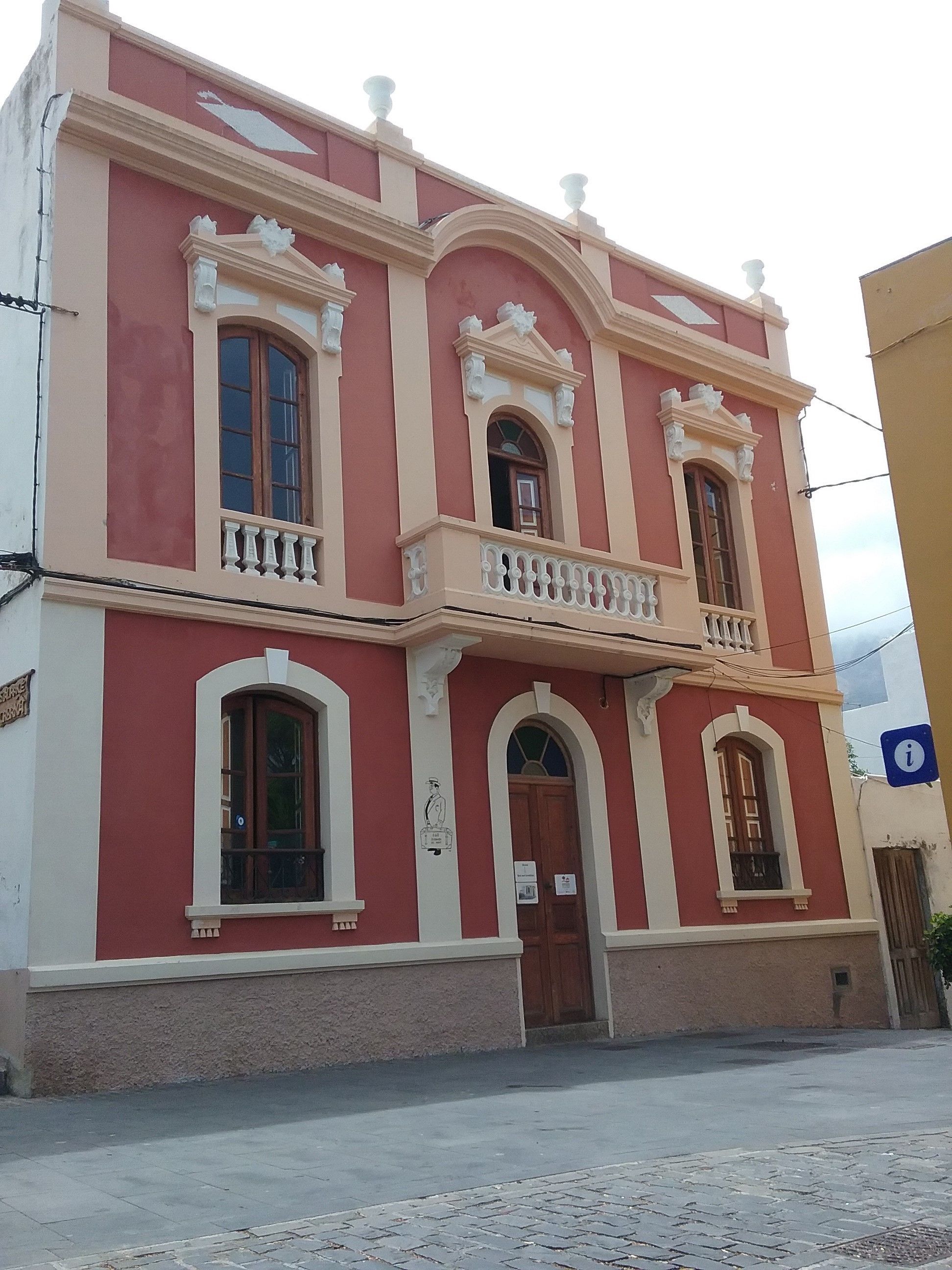 Un bâtiment à deux étages, doté d’une façade rouge, de bordures blanches et d’éléments décoratifs.