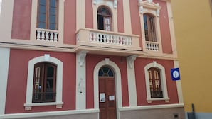 A building with a symmetrical facade, featuring three windows with white frames and decorative moldings. - B&B Buenavista del Norte (Buenavista del Norte)