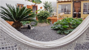 A hammock in a garden area with potted plants, a small table, and a chair. - B&B Buenavista del Norte (Buenavista del Norte)
