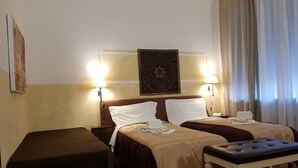 A hotel room with two beds, a bench, and a table. - Locazione Turistica Cittadella (Verona)