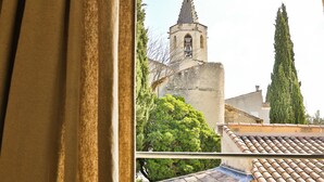 Une vue d’un clocher d’église avec une cloche, entouré d’arbres et de bâtiments.