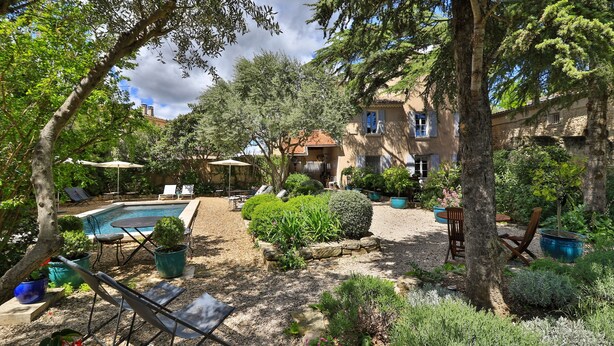 Un espace piscine privé, agrémenté de chaises longues, entouré de plantes en pot et bordé d’un chemin en pierre.