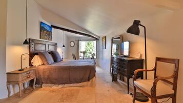 Quarto com cama, mesa de cabeceira, luminária, cômoda, cadeira e janela com vista.