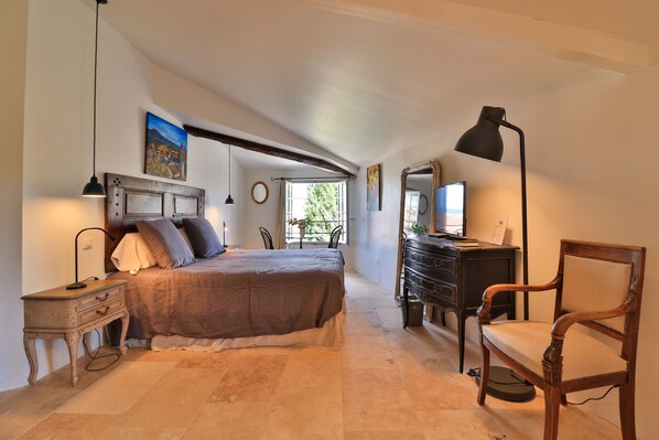 Une chambre à coucher comprenant un lit, une table de chevet, une lampe, une commode, une chaise et une fenêtre donnant sur un paysage agréable.