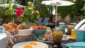 Un plateau de petit-déjeuner comprenant un panier de pain, un bol de fraises, une assiette d’œufs et un verre de jus.