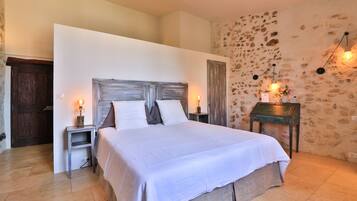 A bedroom with a large bed, a stone wall, and a wooden door.