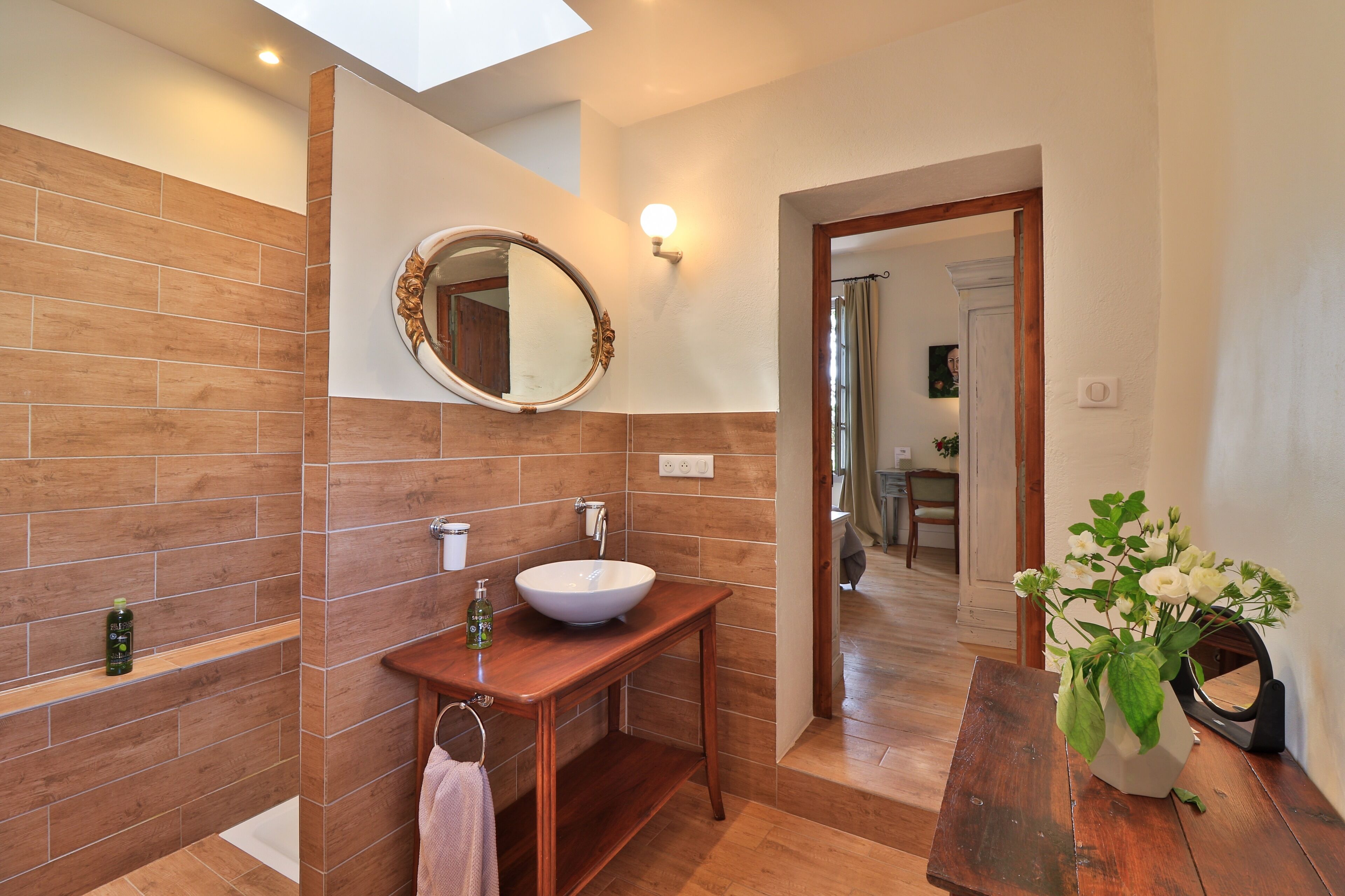 A bathroom with a wooden vanity, a round mirror, and a white sink.