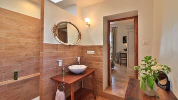 A bathroom with a wooden vanity, a round mirror, and a white sink.