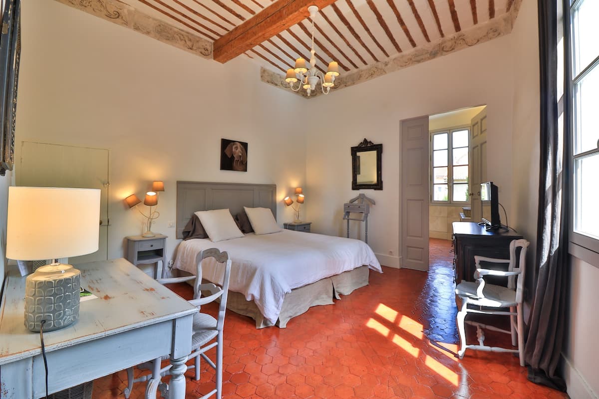 Een slaapkamer met een bed, nachtkastjes, een bureau en een stoel.